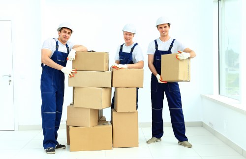 Specialist movers handling an upright piano with protective equipment